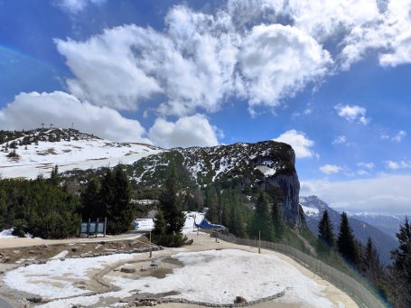 Schneebedeckte Berge unter einem wolkigen Himmel mit einem kurvenreichen Weg.