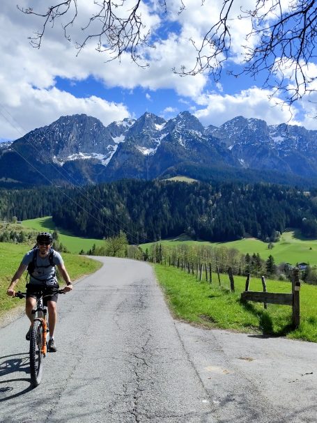 Ein Radfahrer auf einer asphaltierten Straße mit Bergen im Hintergrund.